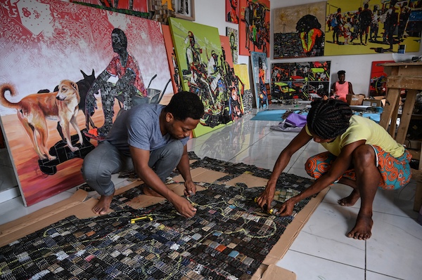 Mounou Désiré Koffi, (à droite), artiste ivoirien écologiste et engagé, donne une seconde vie à de vieux téléphones portables mis au rebut en les recyclant en œuvres d'art colorées. (Sia Kambou/AFP)