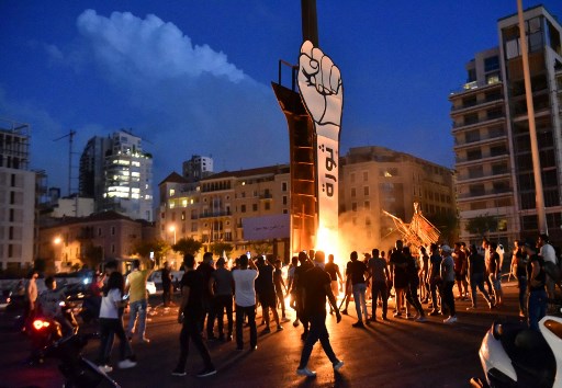 Des jeunes libanais se rassemblent autour du Poing de la Révolution, symbole du soulèvement libanais d'octobre 2019. (AFP)