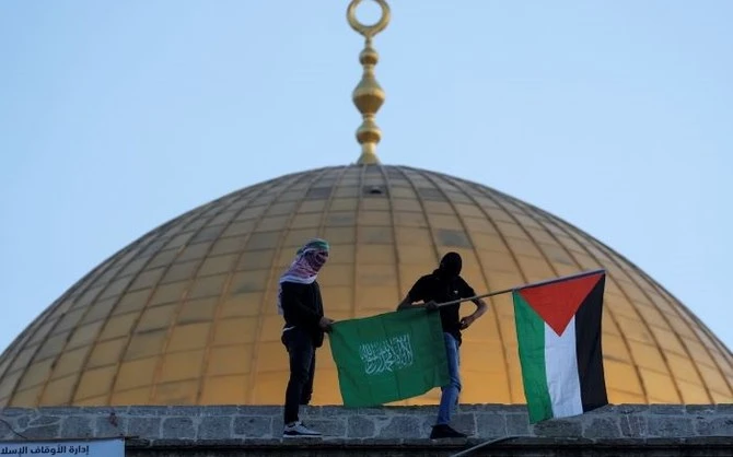 Des Palestiniens masqués avec des drapeaux palestiniens et du Hamas, dans l’enceinte de la mosquée Al-Aqsa, vieille ville de Jérusalem, le 2 mai 2022. (AP Photo)