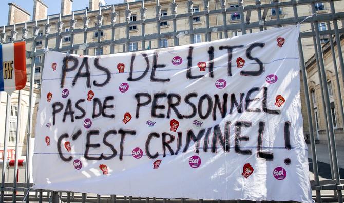 Une photo montre une banderole, sur laquelle on peut lire «Pas de lits, pas de personnel, c'est criminel», aux grilles de l'hôpital Tenon à Paris lors d'un rassemblement d'agents de santé dénonçant la dégradation de leurs conditions de travail, le 25 mai 2022. AFP