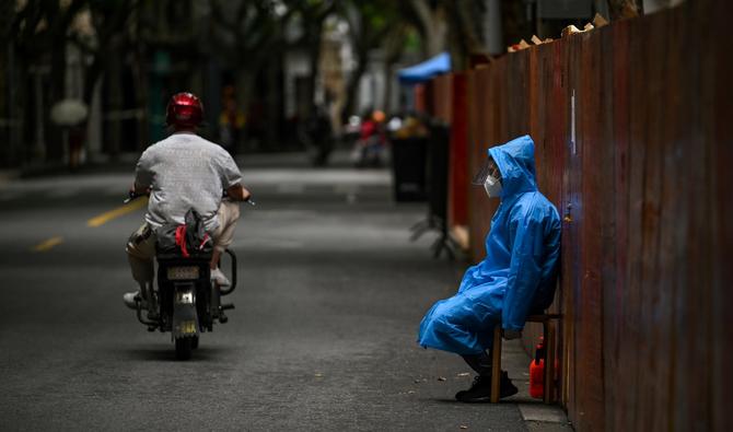Un ouvrier est assis à côté d'une clôture érigée pour fermer une zone résidentielle sous verrouillage de Covid-19 dans le district de Huangpu à Shanghai le 10 juin 2022. (AFP)