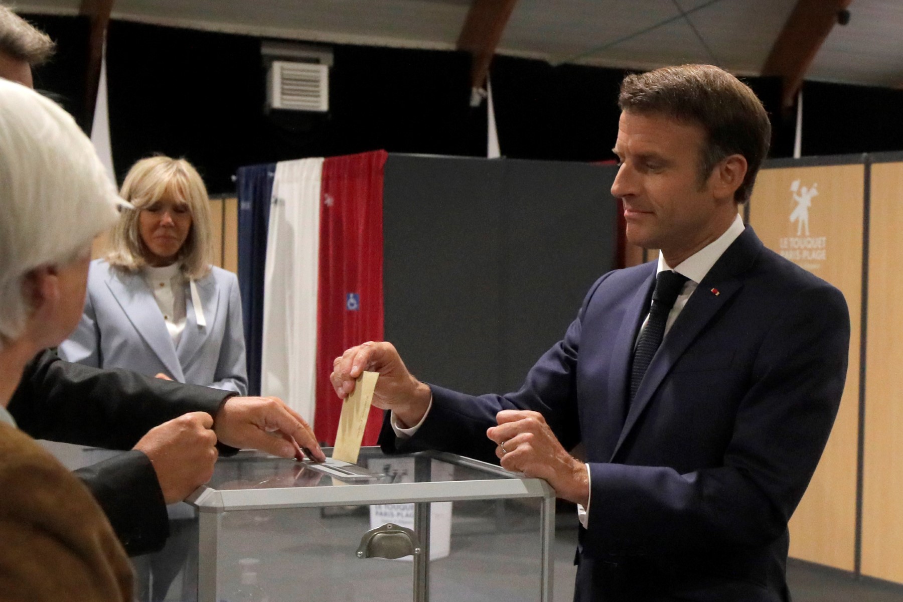 Le président français Emmanuel Macron vote aux côtés de son épouse Brigitte Macron lors de la deuxième étape des élections législatives françaises dans un bureau de vote du Touquet, dans le nord de la France, le 19 juin 2022. (Michel Spingler / POOL / AFP)