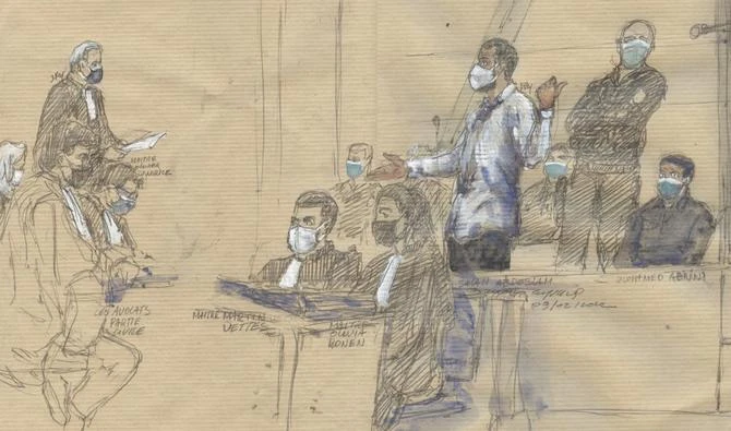 Ce croquis judiciaire réalisé le 9 février 2022 montre l'accusé Salah Abdeslam debout devant la cour d'assises spéciale de Paris, à côté de l'avocat français des proches des victimes des attentats de Paris, Olivier Morice (G) lors du procès des attentats de novembre 2015. (AFP)