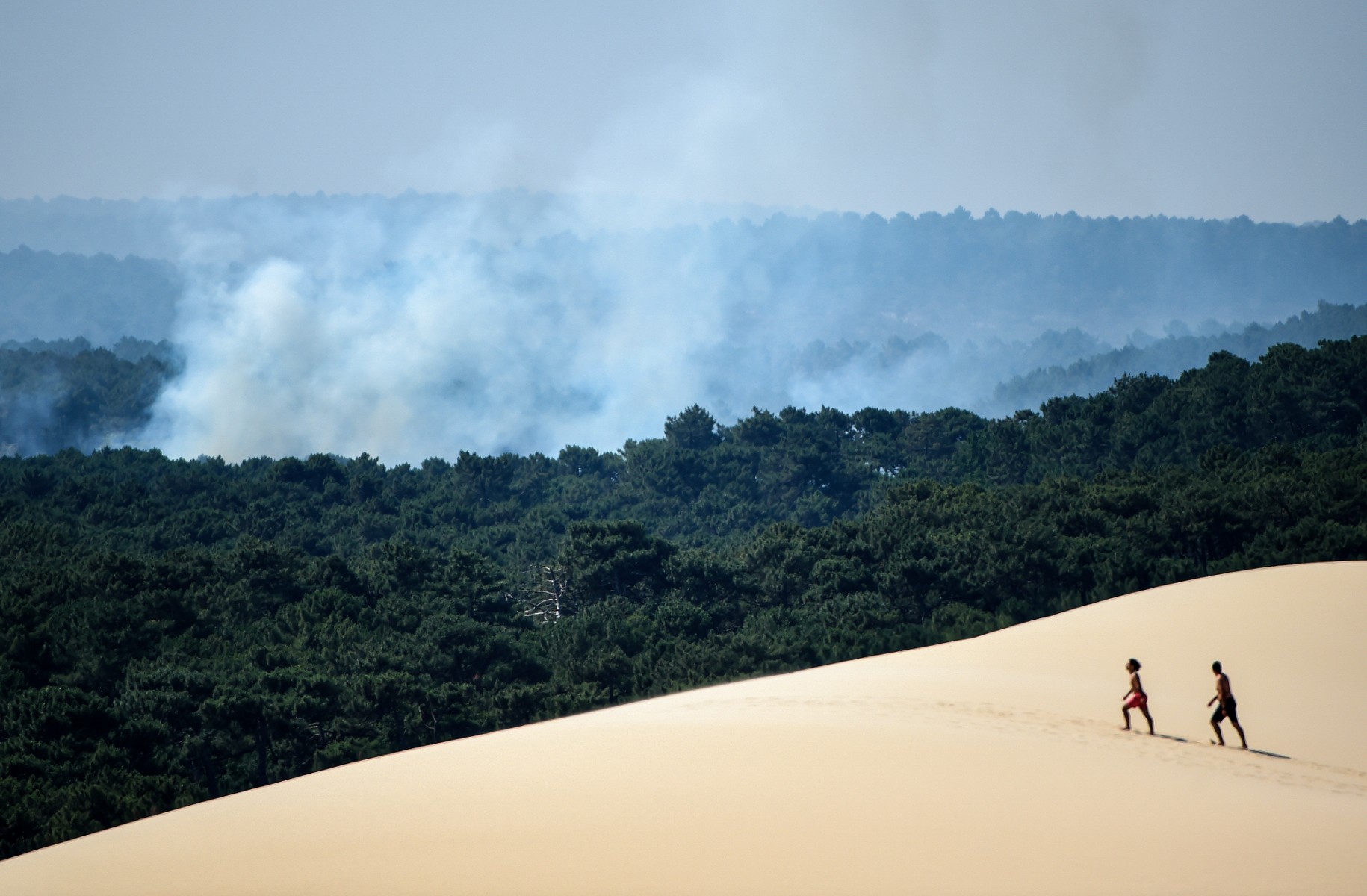 Des personnes marchent sur la dune du Pilat, près de La Teste-de-Buch, dans le sud-ouest de la France, le 16 juillet 2022. L'intense mobilisation des pompiers n'a pas faibli le 16 juillet 2022 pour venir à bout des incendies dans le sud de la France, et notamment en Gironde. (Photo de Gaizka Iroz / AFP)