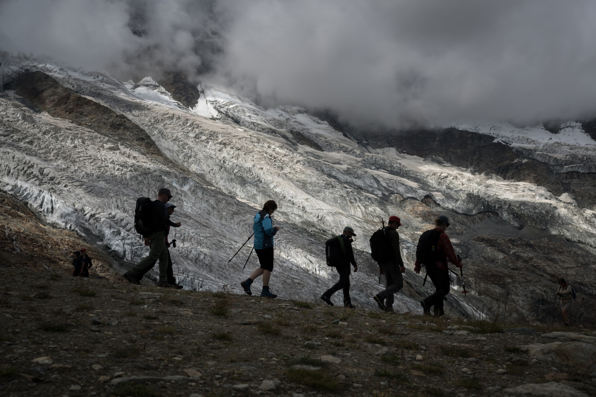 Des randonneurs sont vus en silhouette marchant à côté du glacier de Fee (en allemand : Feegletscher) au-dessus de la station alpine suisse de Saas-Fee, le 30 juillet 2022. (Photo de Fabrice Coffrini / AFP)