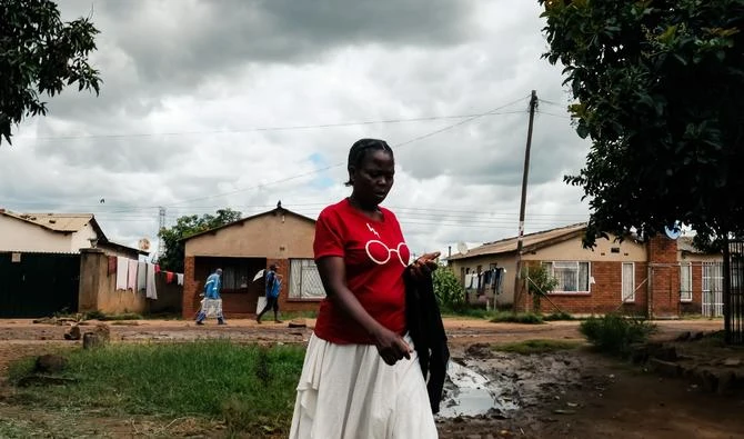 Une femme passe devant une rangée de maisons dans le canton de Kuwadzana à Harare le 23 mars 2022. Les produits d'épicerie achetés par des proches en Afrique du Sud sont livrés à des foyers assez chanceux pour avoir de la famille dans la diaspora. (AFP)