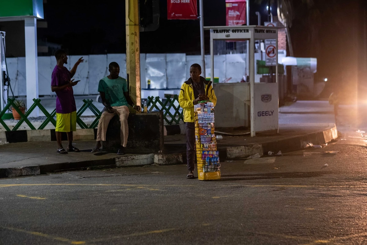 Des vendeurs de cigarettes et de chewing-gum se bousculent devant une boîte de nuit à Ikoyi, Lagos, le 23 juillet 2022. Dans le quartier aisé d'Ikoyi, le flux de personnes courant après l'argent ne s'arrête jamais. (Photo : Benson Ibeabuchi / AFP)