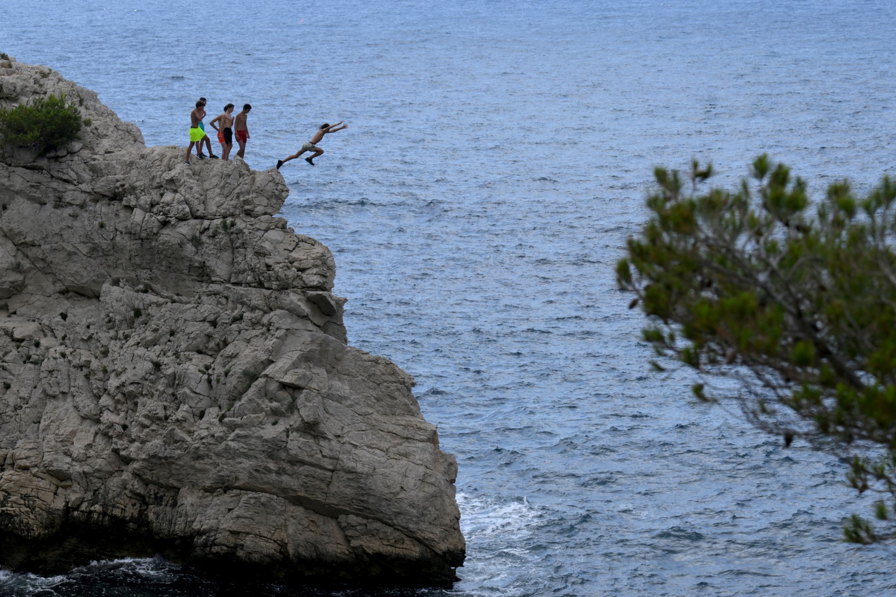 Des personnes sautent d'une falaise dans le parc national des Calanques à Marseille, dans le sud de la France, le 24 juin 2022. (Photo de Nicolas TUCAT / AFP)