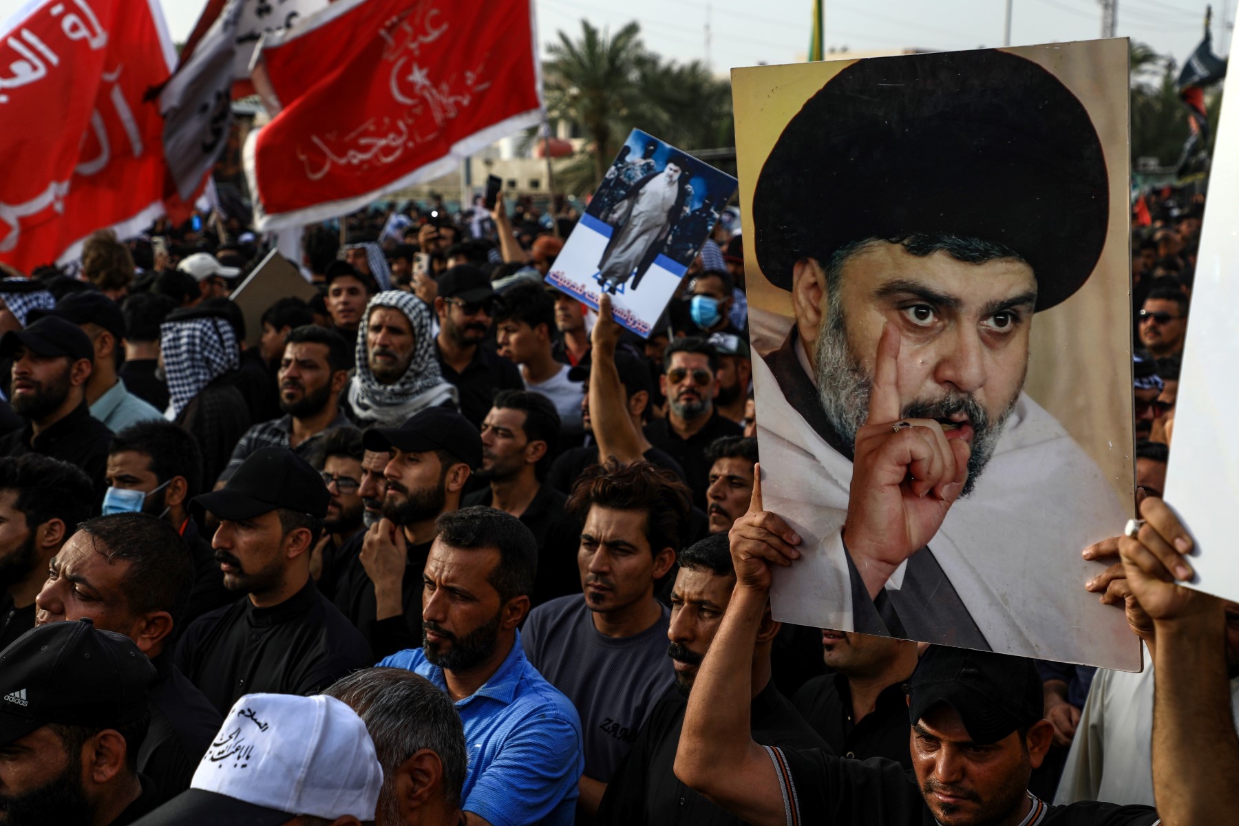 Des partisans portent des portraits du religieux chiite Moqtada Sadr alors qu'ils se rassemblent dans la ville de Nasiriyah, dans la province de Dhi Qar, dans le sud de l'Irak, le 12 août 2022, pour protester contre la nomination au poste de Premier ministre d'un membre d’une faction chiite rivale. (Photo par Asaad NIAZI / AFP)