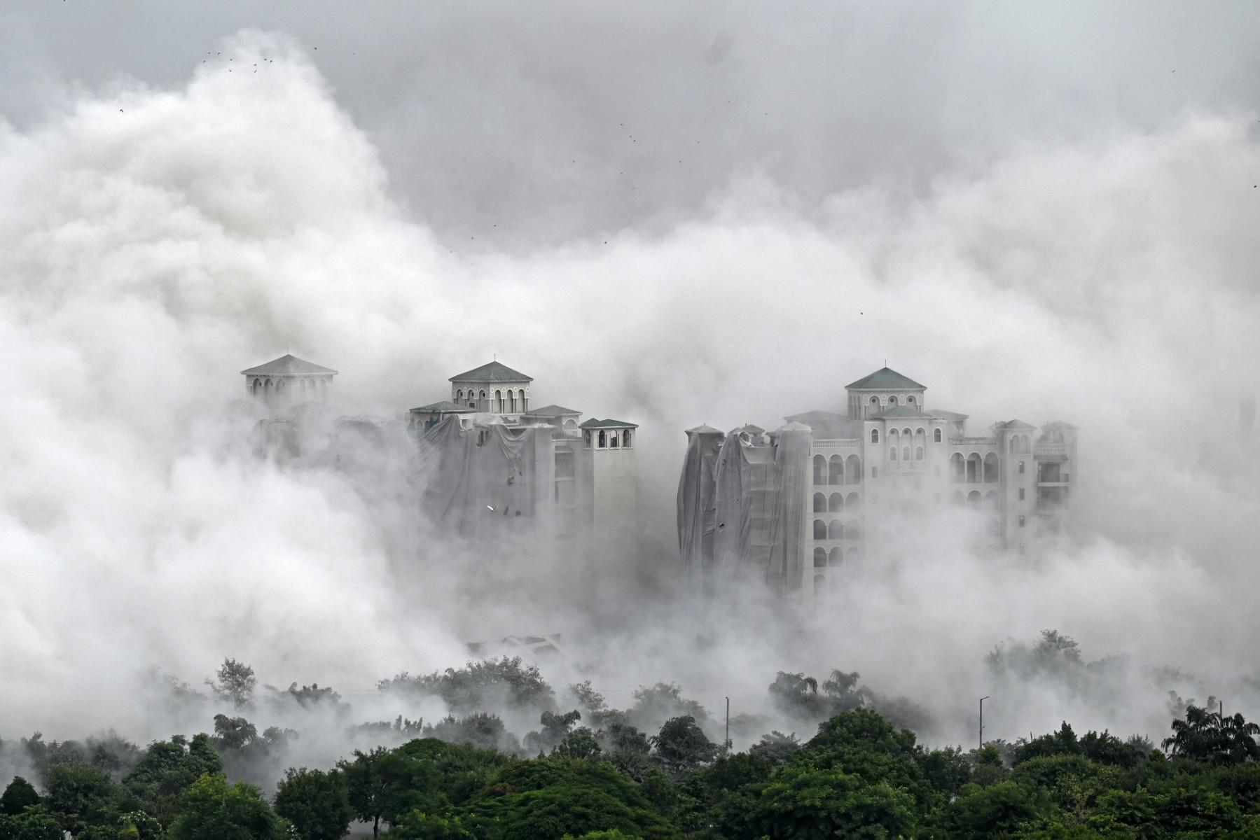 Des immeubles résidentiels sont engloutis dans la poussière après qu'une implosion contrôlée a démoli les "Twin Towers" résidentielles de 100 mètres de haut à Noida, dans la banlieue de New Delhi, le 28 août 2022. (Photo de Sajjad HUSSAIN / AFP)