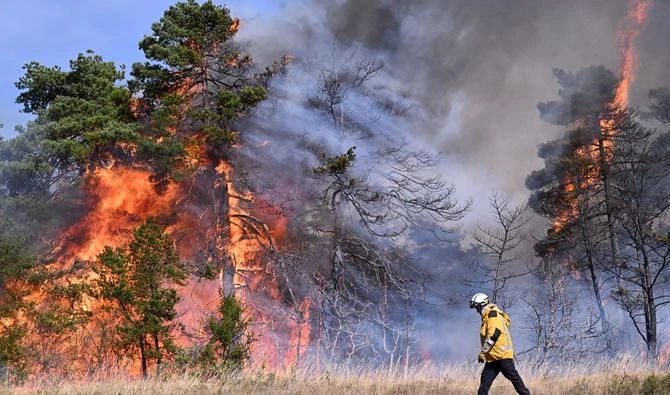 Un pompier marche devant des arbres en flammes lors d'un incendie de forêt à Boyne, dans le sud de la France, dans le "Parc naturel des Grands Causses" le 9 août 2022. (AFP)