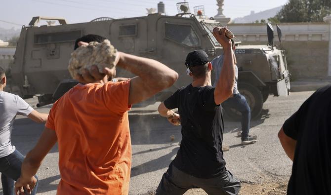 Des jeunes Palestiniens lancent des pierres sur une jeep de l'armée israélienne dans la ville de Silwad, près de la ville de Ramallah en Cisjordanie occupée, après une opération militaire dans la ville, le 31 août 2022. (AFP)