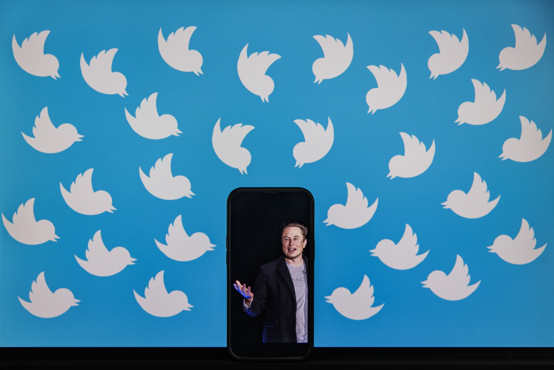 Cette photo d'illustration prise le 5 août 2022 montre un téléphone portable affichant une photo d'Elon Musk placée sur un écran d'ordinateur rempli de logos Twitter à Washington, DC. (Photo : Samuel Corum / AFP)