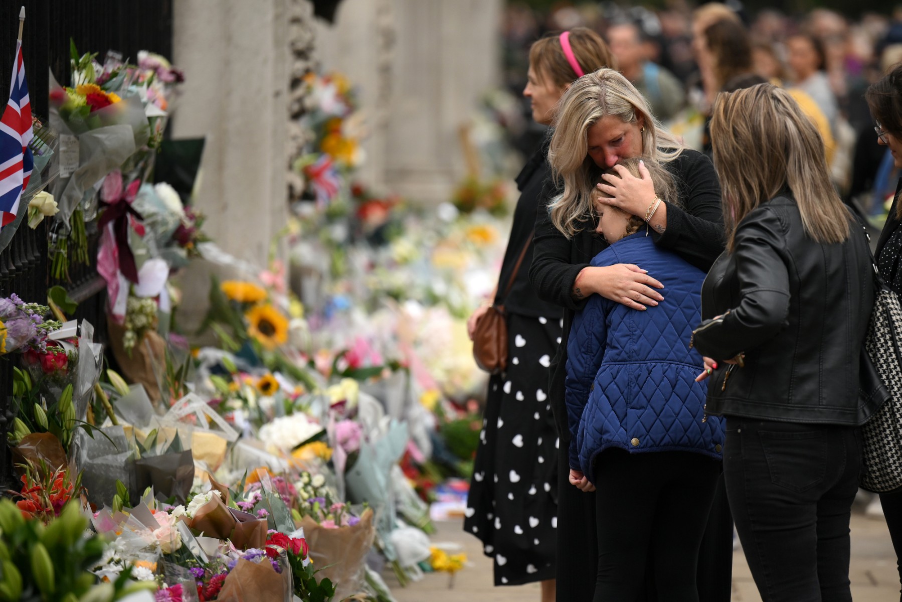 Des personnes réagissent après avoir déposé des fleurs et des hommages au palais de Buckingham à Londres, le 9 septembre 2022, un jour après le décès de la reine Elizabeth II à l'âge de 96 ans (Photo : Daniel LEAL / AFP)