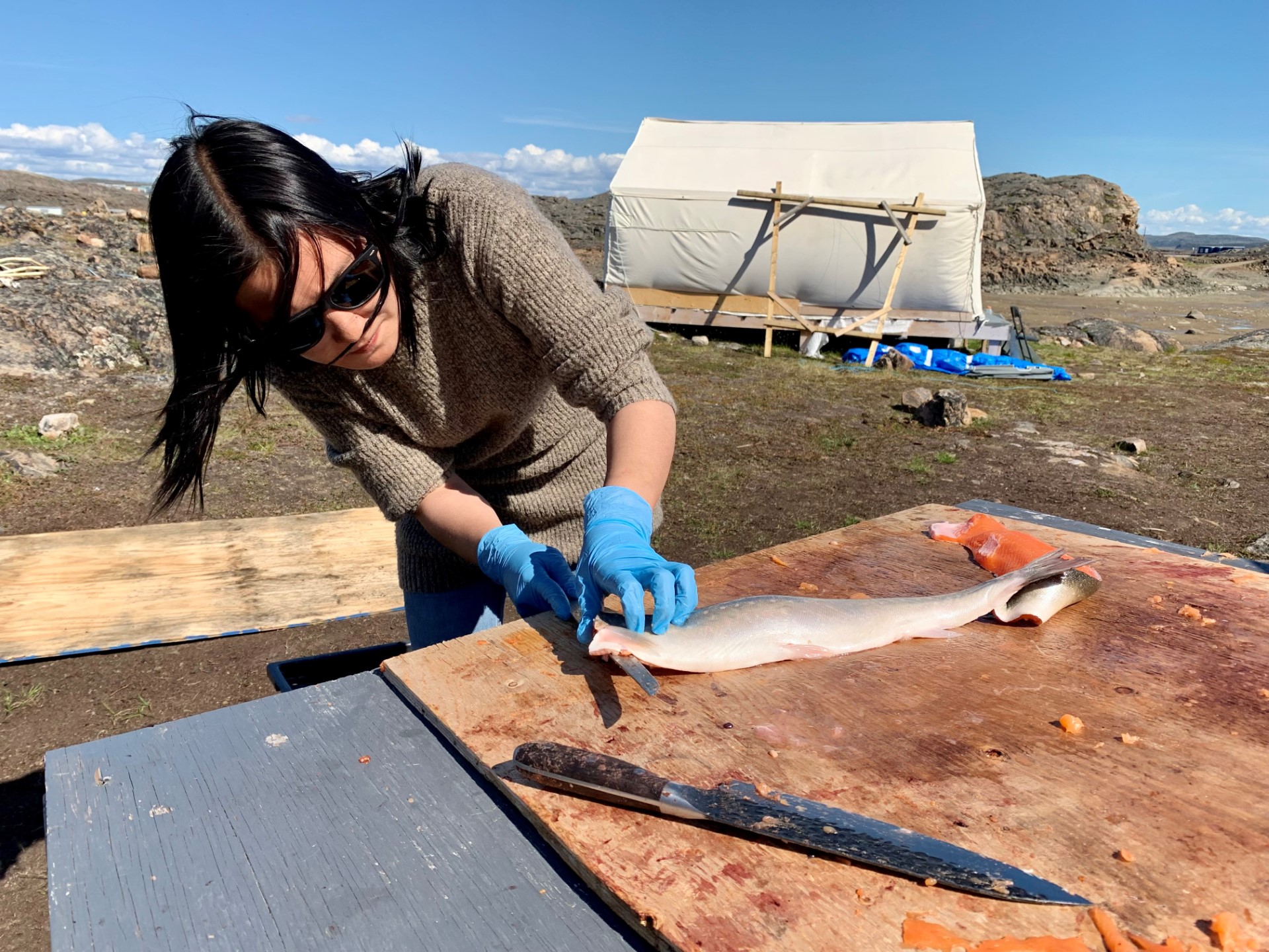 Annie Kootoo, 22 ans, prépare du saumon à Iqaluit, Nunavut, Canada, le 27 juillet 2022. (Photo par Anne-Sophie THILL / AFP)