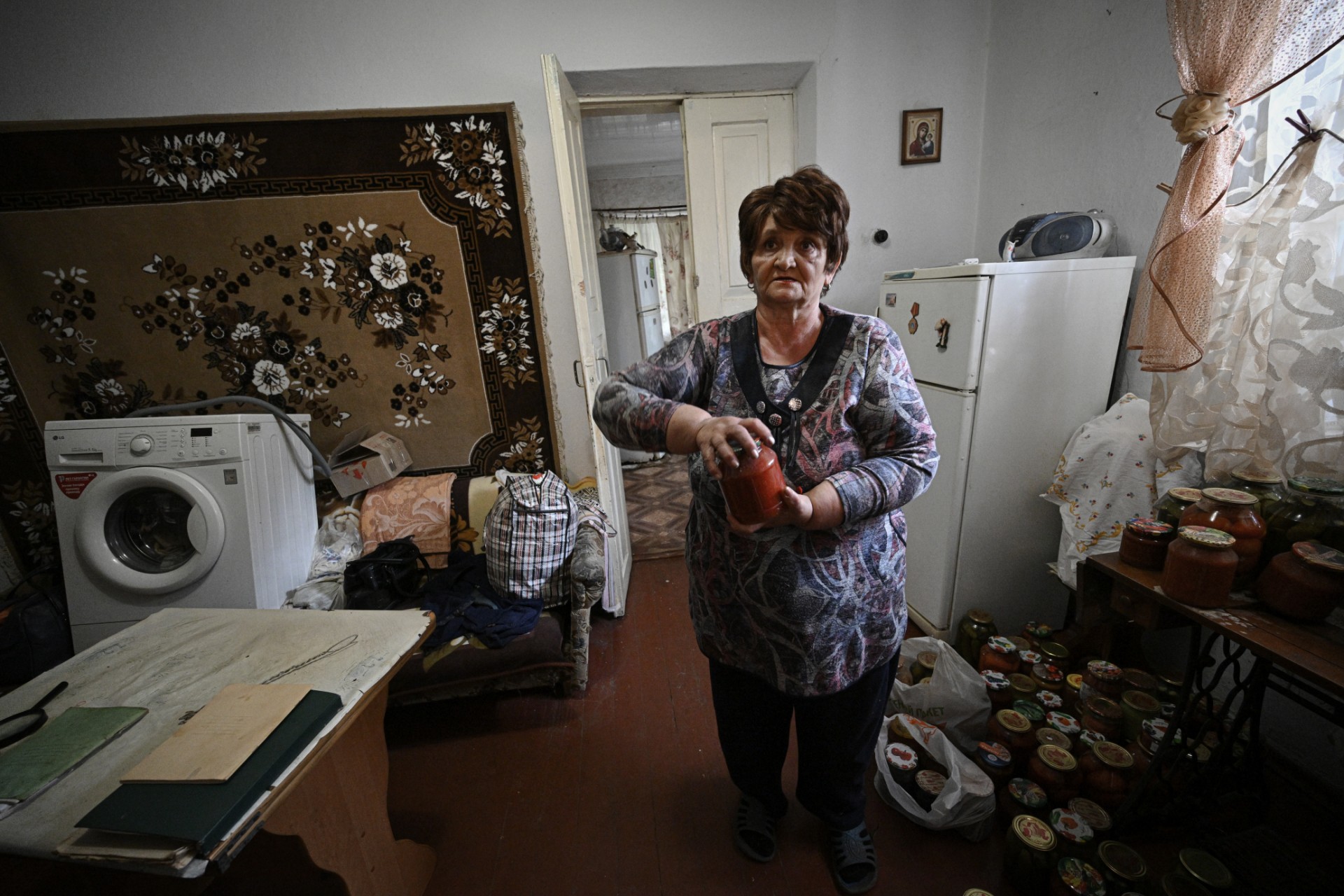 Cette photo prise le 15 septembre 2022 montre Lubov, 69 ans, tenant des bocaux à fruits récupérés dans la cave de sa maison endommagée par l'eau dans la ville de Kryvyi Rih, où des dizaines de maisons ont été inondées après qu'une attaque russe a endommagé un barrage en amont le 14 septembre. (photo Genya SAVILOV / AFP).