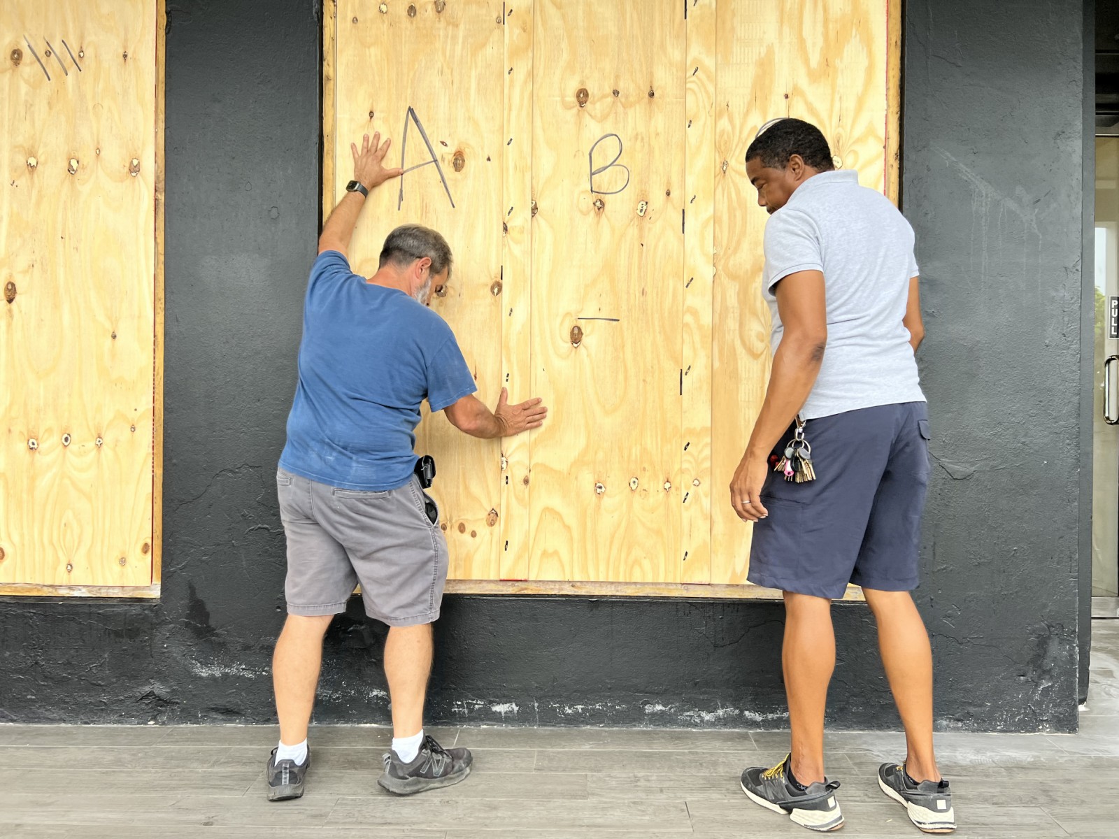 Deux hommes barricadent un magasin à Hamilton le 22 septembre 2022. L'ouragan Fiona se dirigeait mercredi vers les Bermudes sous la forme d'une puissante tempête de catégorie 4. (Photo de Sébastien VUAGNAT / AFP)