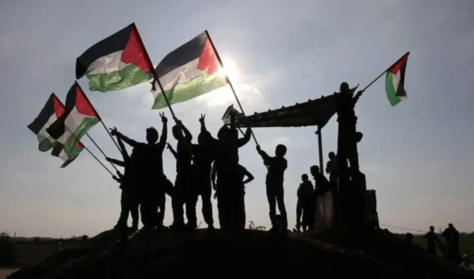 Des Palestiniens brandissent leur drapeau national près de la frontière entre Israël et Gaza. (AFP/Archives)