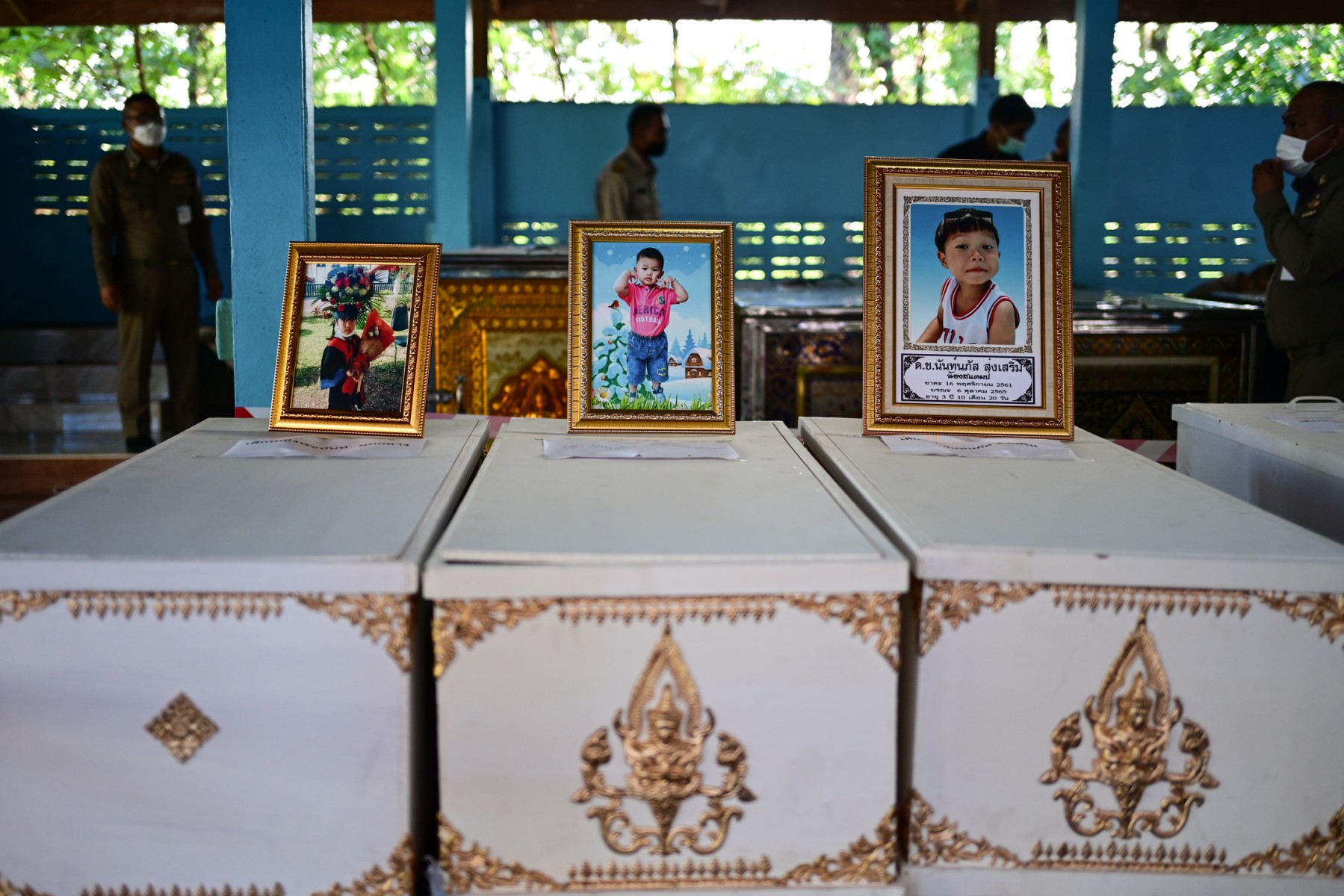 Les portraits des jeunes victimes d'une fusillade dans une crèche sont exposés sur leurs cercueils alors que les préparatifs des funérailles sont en cours au temple Wat Si Uthai, dans la province de Nong Bua Lam Phu, dans le nord-est de la Thaïlande, le 7 octobre 2022. (Photo de Manan Vatsyayana / AFP)
