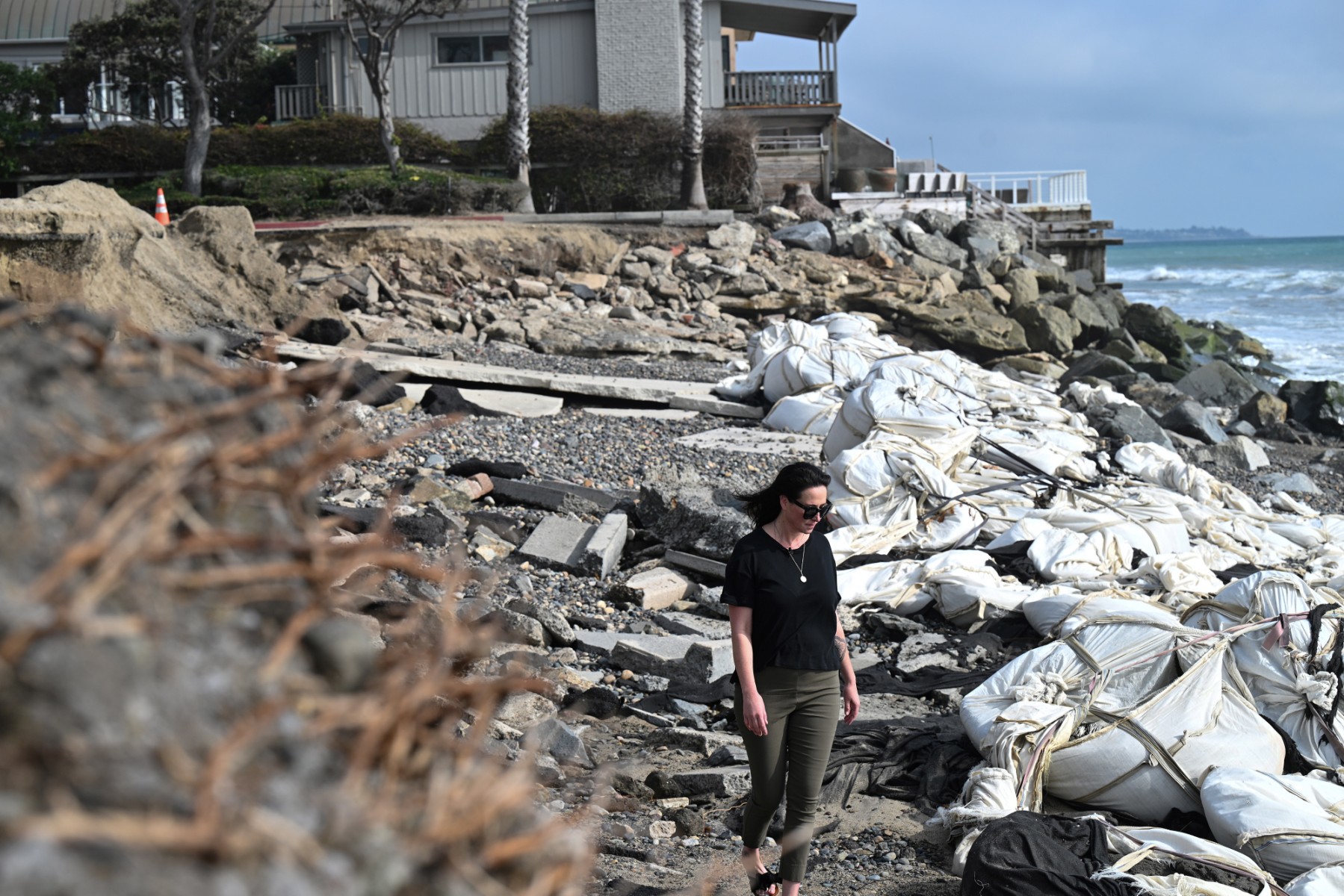 La défenseuse de l'environnement Stefanie Sekich-Quinn, de la Surfrider Foundation, marche parmi des paysages de plage et de parc détruits et des sacs de sable placés dans le but d'arrêter la perte de sable de plage due à l'érosion côtière, à Capistrano Beach, à Dana Point, en Californie, le 12 octobre 2022. (Photo de Robyn Beck / AFP)