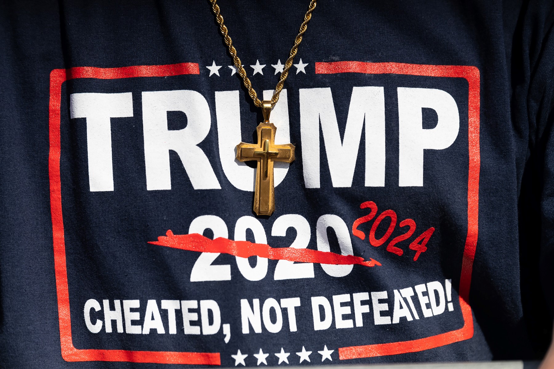 Sur cette photo d'archive prise le 23 avril 2022, un homme porte une croix avec un t-shirt Trump sur lequel on peut lire "Trump 2024, abusé, pas défait en 2020" lors du rassemblement de l'ancien président américain Donald Trump à Delaware, Ohio. (Photo par Megan Jelinger / AFP)