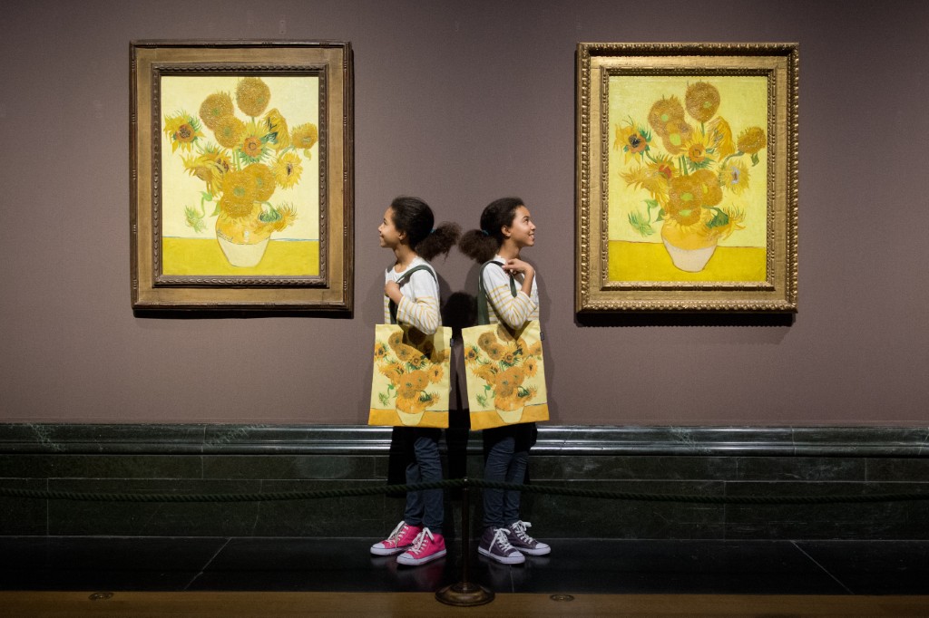 Les jumelles identiques Ella (à gauche) et Eva posent pour des photos avec deux versions des tableaux Tournesols de l'artiste néerlandais Vincent van Gogh à la National Gallery de Londres, le 24 janvier 2014. (Photo de Leon Neal / AFP)