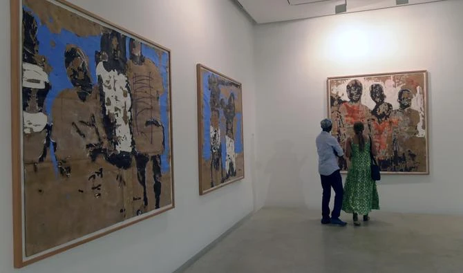 Un couple regarde les œuvres du peintre ivoirien Armand Boua exposées à la galerie Cecile Fakhoury à Abidjan le 23 août 2019. (AFP)