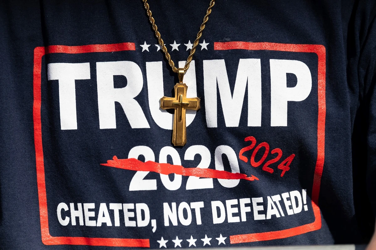 Sur cette photo d'archive prise le 23 avril 2022, un homme porte une croix avec un t-shirt Trump sur lequel on peut lire "Trump 2024, abusé, pas défait en 2020" lors du rassemblement de l'ancien président américain Donald Trump à Delaware, Ohio. (Photo par Megan Jelinger / AFP)