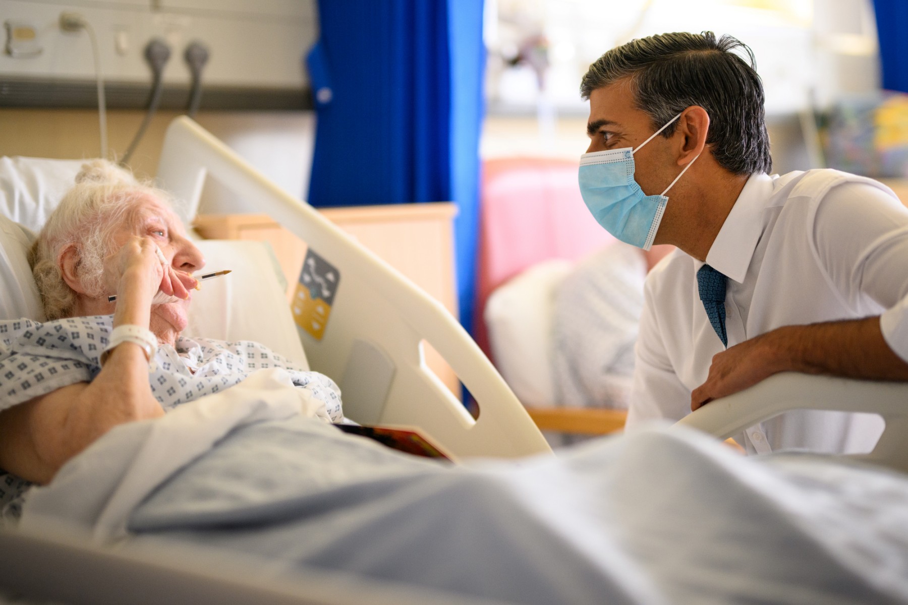 Le Premier ministre britannique Rishi Sunak, portant un masque sanitaire, parle avec la patiente Brenda Boyling lors de sa visite à l'hôpital universitaire de Croydon, dans le sud de Londres, le 28 octobre 2022. (Photo : Leon Neal / Pool / AFP)