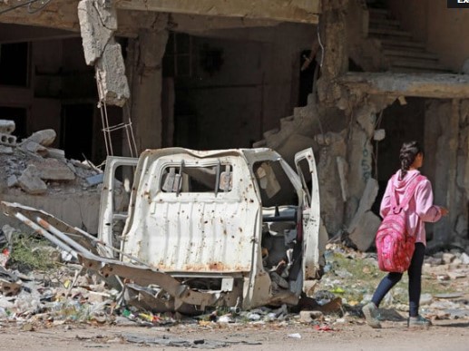 Une jeune fille passe devant un véhicule endommagé et un bâtiment détruit dans le camp de réfugiés de Yarmuk, dans la banlieue sud de Damas, le 2 novembre 2022. (Photo, AFP)
