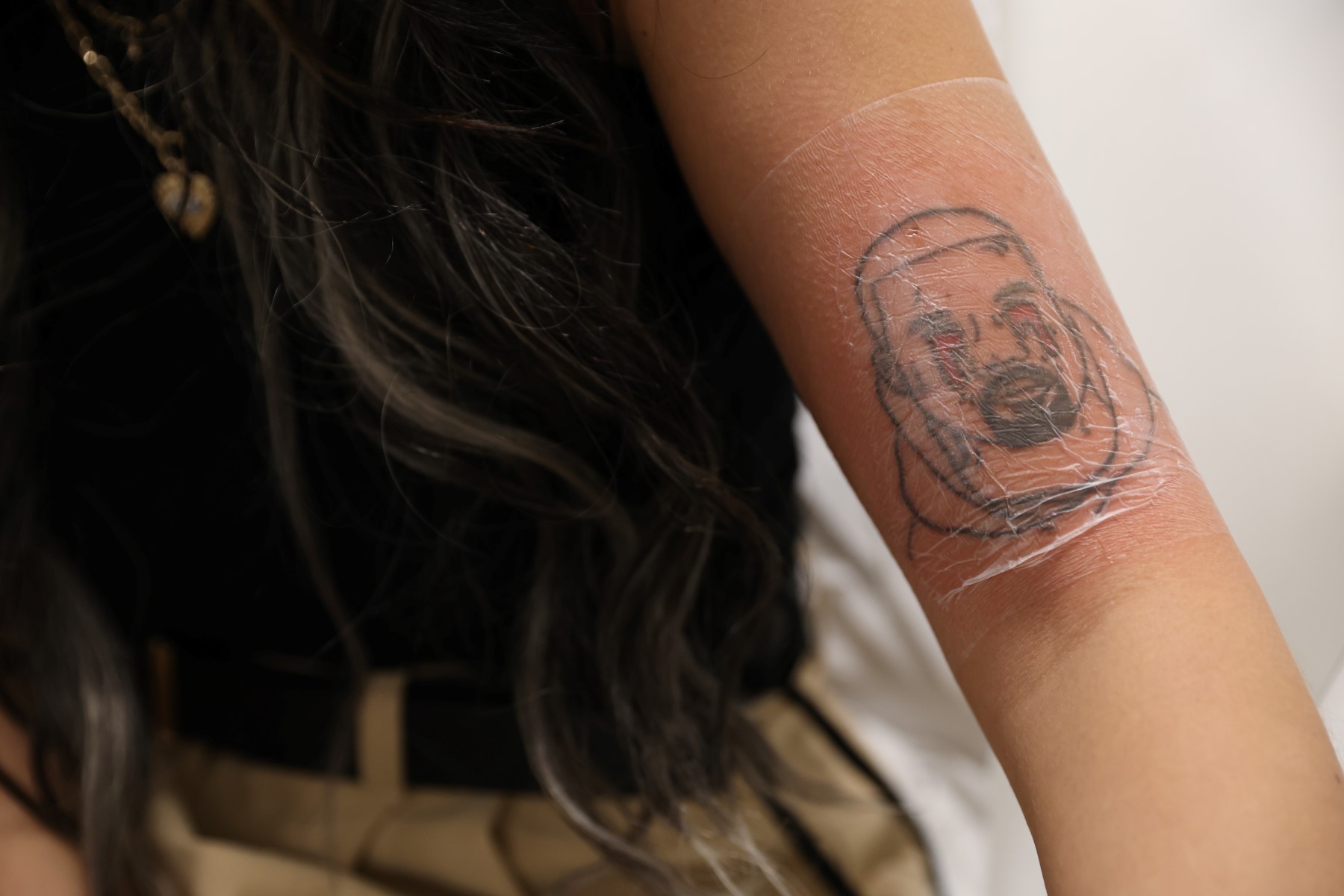 Une cliente, Kimberly Westgarth, assise aux Studios NAAMA, une clinique de détatouage à Marylebone, Londres, le 14 décembre 2022, montre son tatouage représentant le chanteur américain Kanye West. (Photo par Isabel Infantes / AFP)