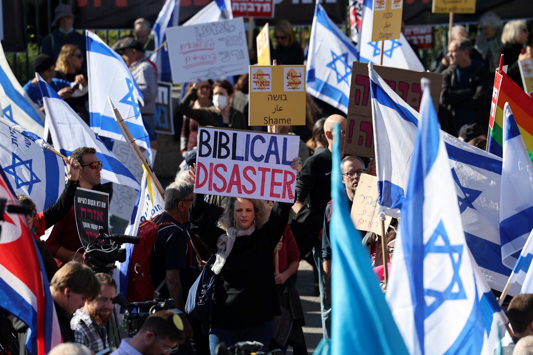 Des militants israéliens brandissent des drapeaux et des pancartes alors qu'ils manifestent devant la Knesset (parlement israélien) à Jérusalem, le 29 décembre 2022, contre l'assermentation du gouvernement de droite. (Photo par Ahmad Gharabli / AFP)