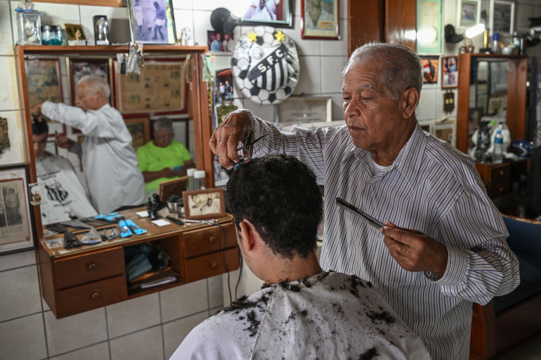 Le barbier Joao Araujo, dit Didi, qui a coupé les cheveux de la légende du football brésilien Pelé, travaille dans son salon de coiffure à Santos, au Brésil, le 30 décembre 2022. (Photo de Nelson Almeida / AFP)