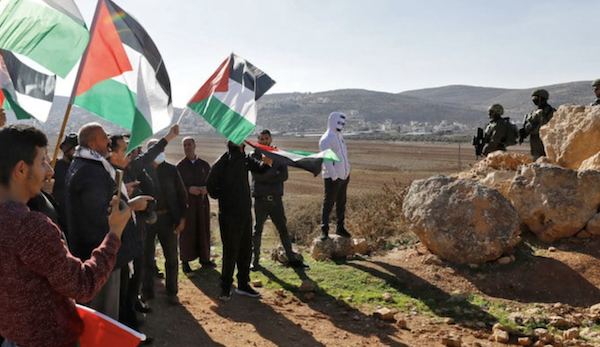 Les forces de sécurité israéliennes prennent position alors que des Palestiniens agitent des drapeaux nationaux lors d’une manifestation à Beit Dajan, à l’est de la ville occupée de Naplouse, en Cisjordanie, contre l’établissement d’avant-postes israéliens, le 2 décembre 2022. (AFP)