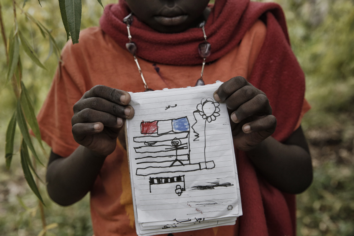 Un enfant montre son dessin dans le jardin de Françoise Cotta, une citoyenne française qui héberge des migrants arrivés illégalement d'Italie, le 25 octobre 2016 à Breil-sur-Roya, un vieux village franco-italien près de Menton. (Photo de Marco Bertorello / AFP)
