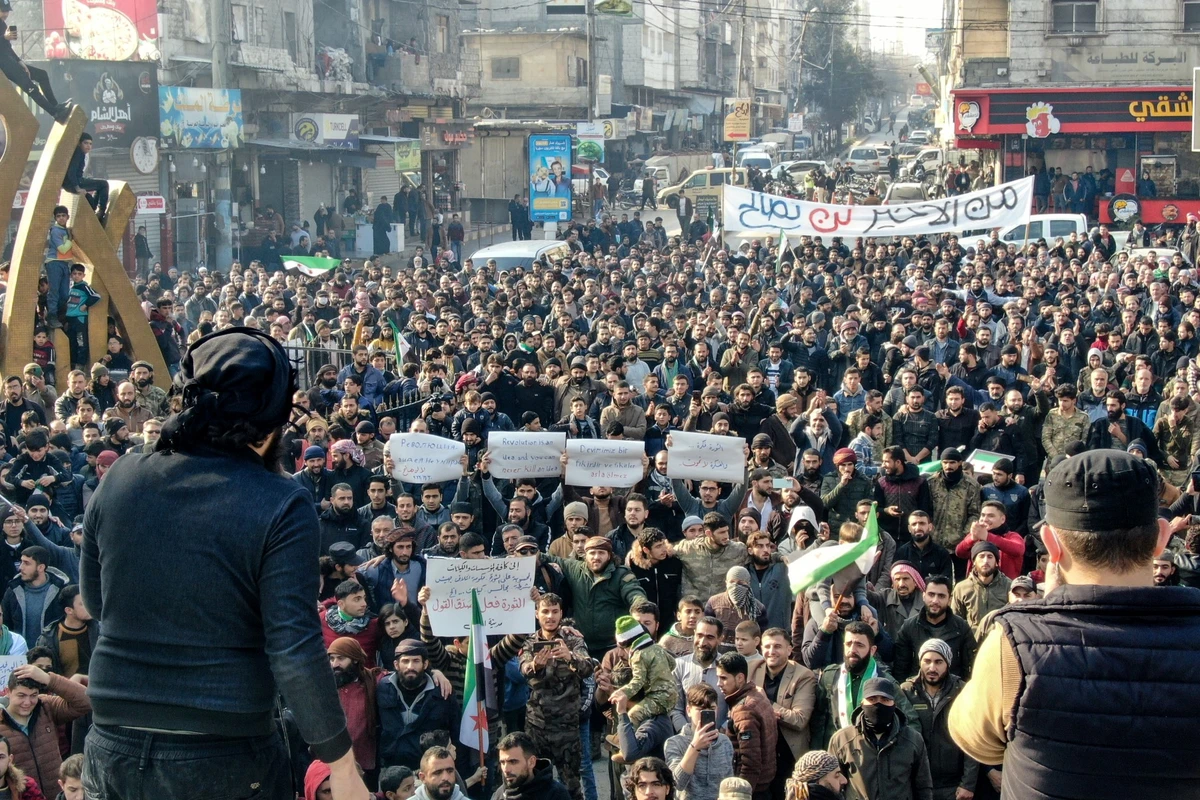 Des manifestants brandissent des drapeaux et des pancartes de l'opposition syrienne lors d'un rassemblement contre un éventuel rapprochement entre Ankara et le régime syrien, le 30 décembre 2022, dans la ville d'al-Bab, tenue par l'opposition, à la frontière avec la Turquie, dans la province d'Alep, au nord de la Syrie. (Photo de Bakr ALKASEM / AFP)