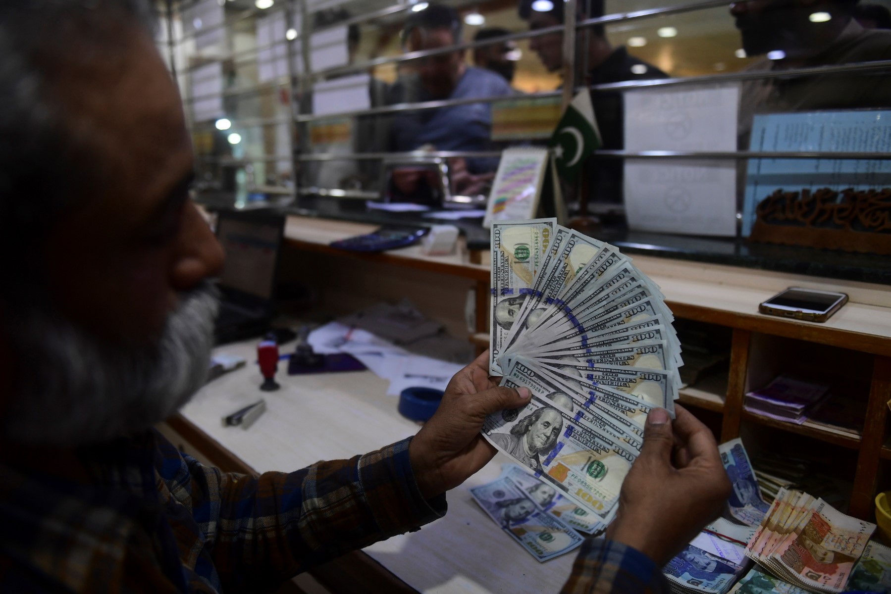 Sur cette photo prise le 10 janvier 2023, un changeur compte des dollars américains sur un marché de change à Karachi. (Photo par Asif HASSAN / AFP)