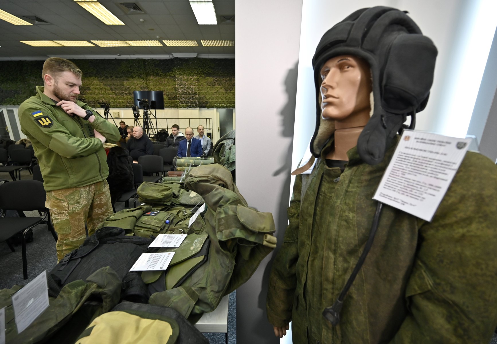 Un officier ukrainien examine l'équipement et les fournitures des envahisseurs russes, saisis par les forces ukrainiennes et exposés avant un briefing des représentants des forces de sécurité et de défense ukrainiennes dans le centre des médias militaires à Kiev, le 12 janvier 2023. (Photo de Genya SAVILOV / AFP)