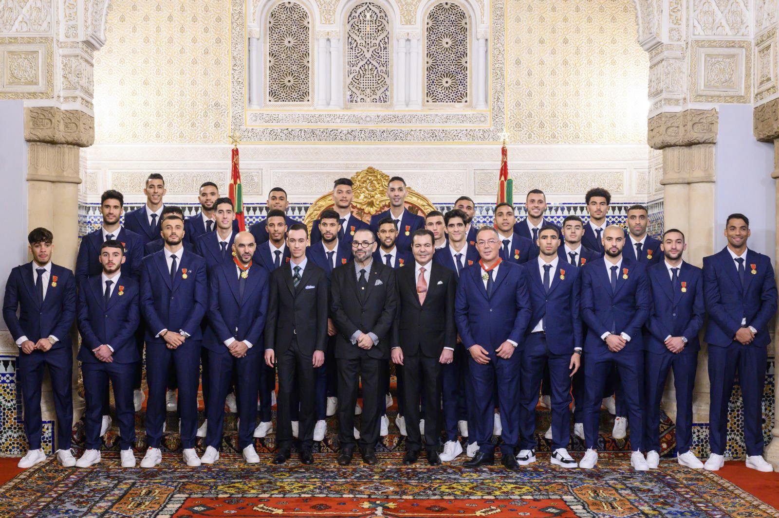Cette photo distribuée par l'Agence nationale de presse marocaine, le 20 décembre 2022, montre le roi du Maroc Mohammed VI (au centre) posant pour une photo avec les joueurs de l'équipe nationale de football du pays au palais royal de Rabat, à leur retour après la Coupe du monde Qatar 2022. (Photo par MAP / AFP)