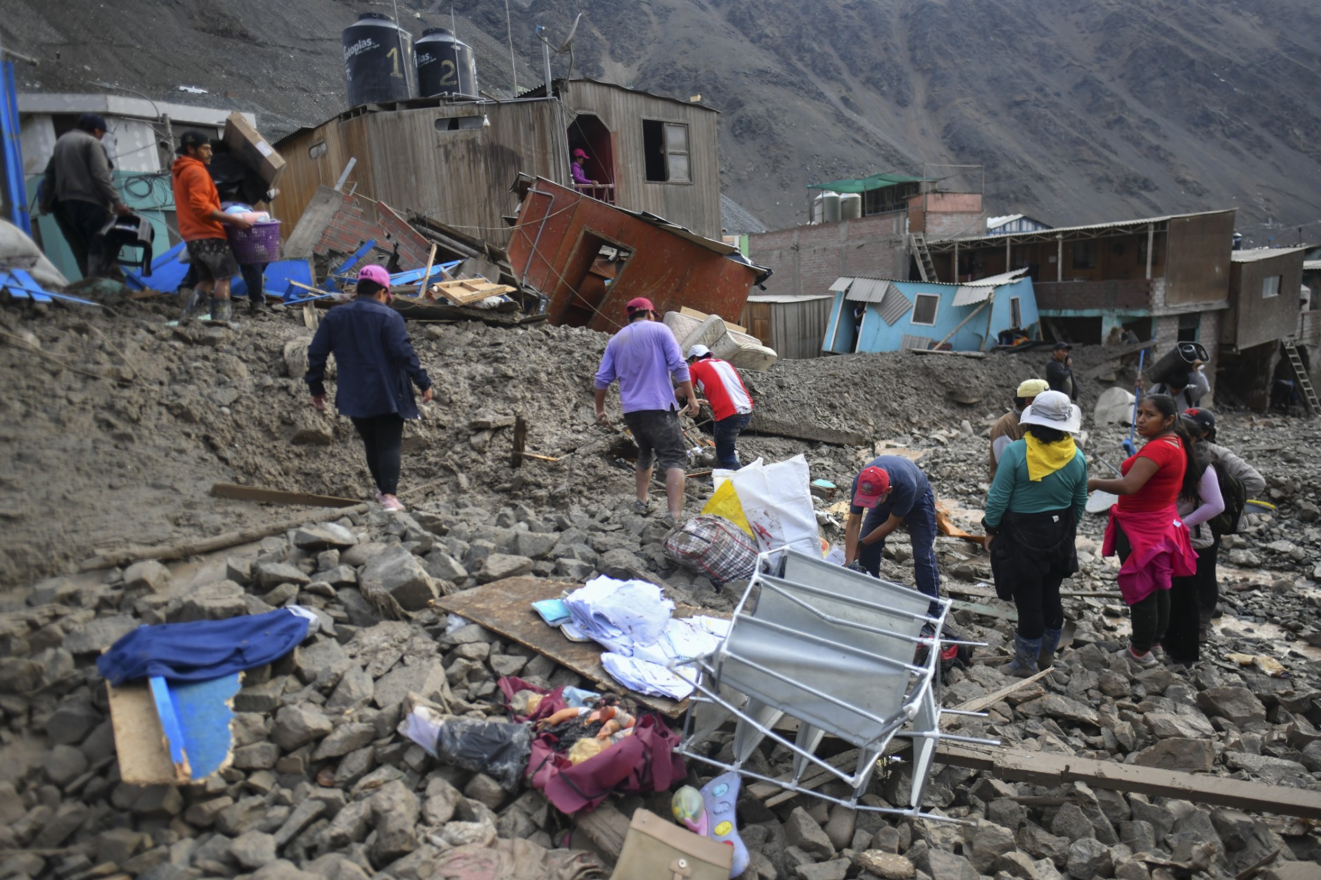 Des habitants du village isolé de Camana, à 840 kilomètres au sud de Lima, marchent parmi les débris laissés après un glissement de terrain au Pérou, le 6 février 2023. (Photo de Diego Ramos / AFP)