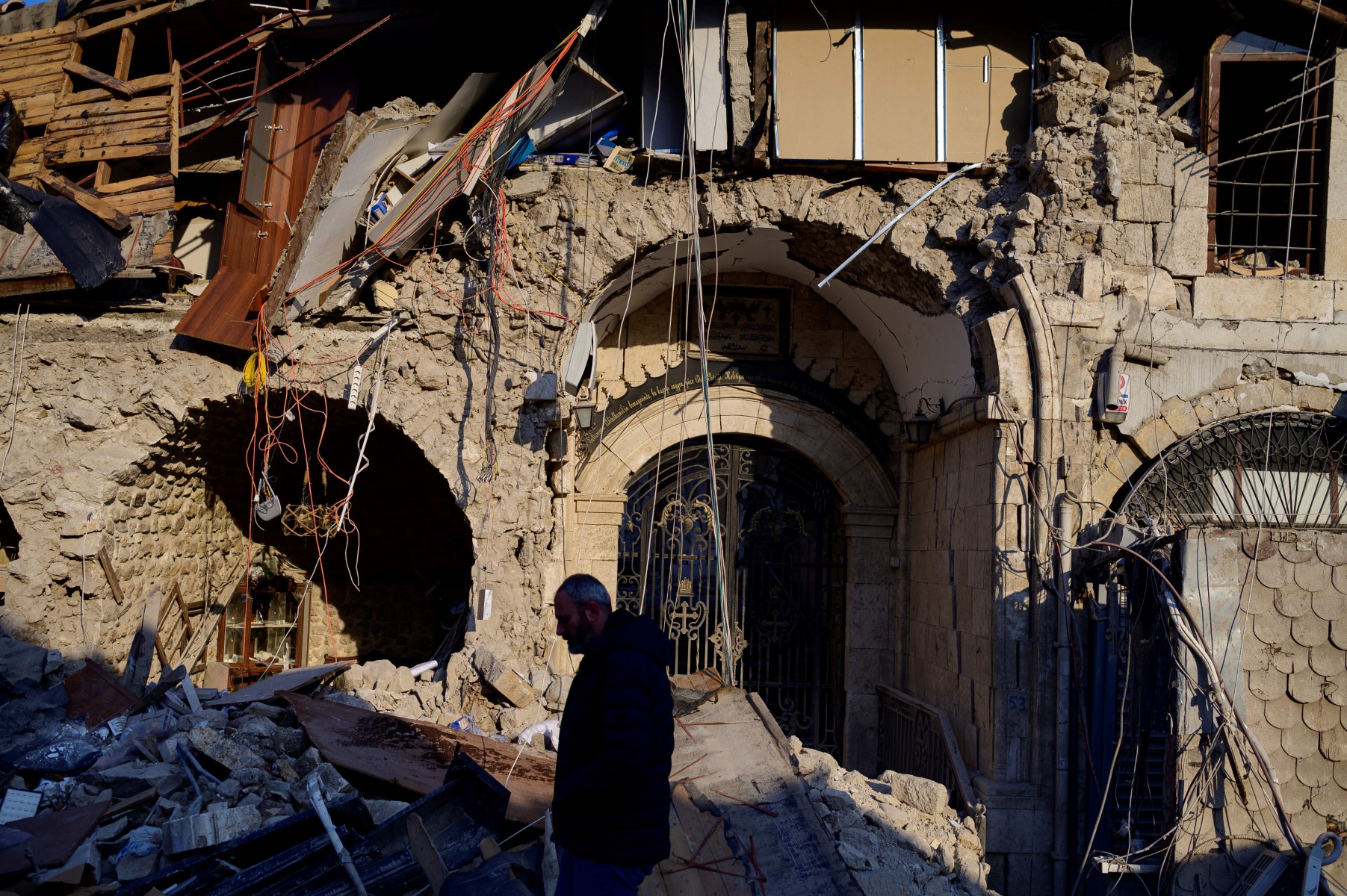 Sertac Paul Bozkurt, fidèle chrétien local de l'Église orthodoxe d'Antioche, marche près de l'Église orthodoxe grecque détruite dans la ville historique d'Antakya, dans le sud du pays, le 12 février 2023, après qu'un tremblement de terre de magnitude 7,8 a frappé la région frontalière de la Turquie et de la Syrie plus tôt dans la semaine. (Photo de Yasin AKGUL / AFP)