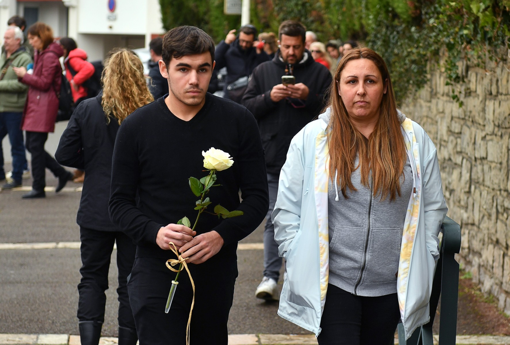 Des personnes en deuil arrivent pour déposer une fleur au collège Saint-Thomas d'Aquin, où une enseignante est morte après avoir été poignardée par un élève, à Saint-Jean-de-Luz, dans le sud-ouest de la France, le 22 février 2023. (Photo de Gaizka Iroz / AFP)