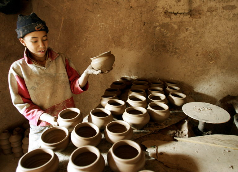 Un jeune ouvrier marocain fabrique des pots avant de les aligner devant son atelier dans le village des potiers à Marrakech, le 12 décembre 2004. (Photo de Jack Guez / AFP)