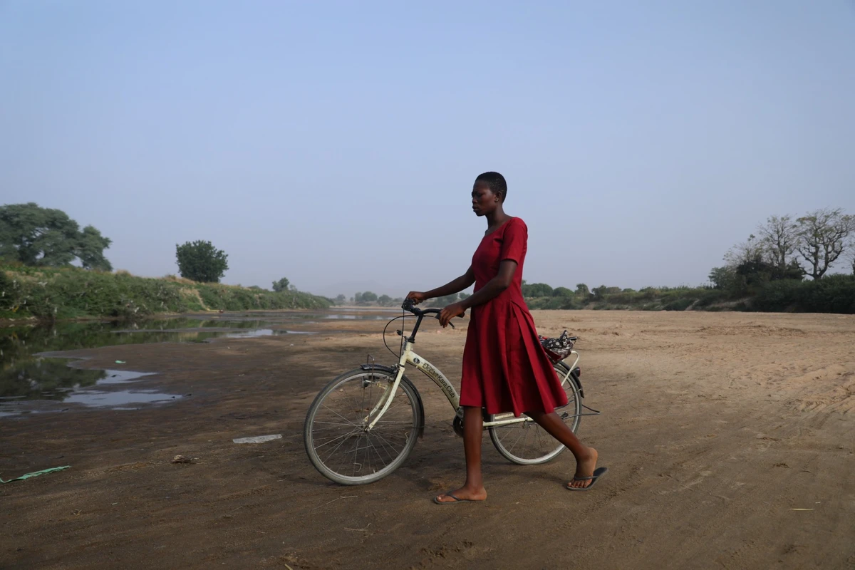 Une femme traverse le lit asséché de la Volta blanche vers le Burkina Faso depuis Issakateng-Bausi, à Bawku, dans le nord du Ghana, le 7 décembre 2022. (Photo de Nipah Dennis / AFP)