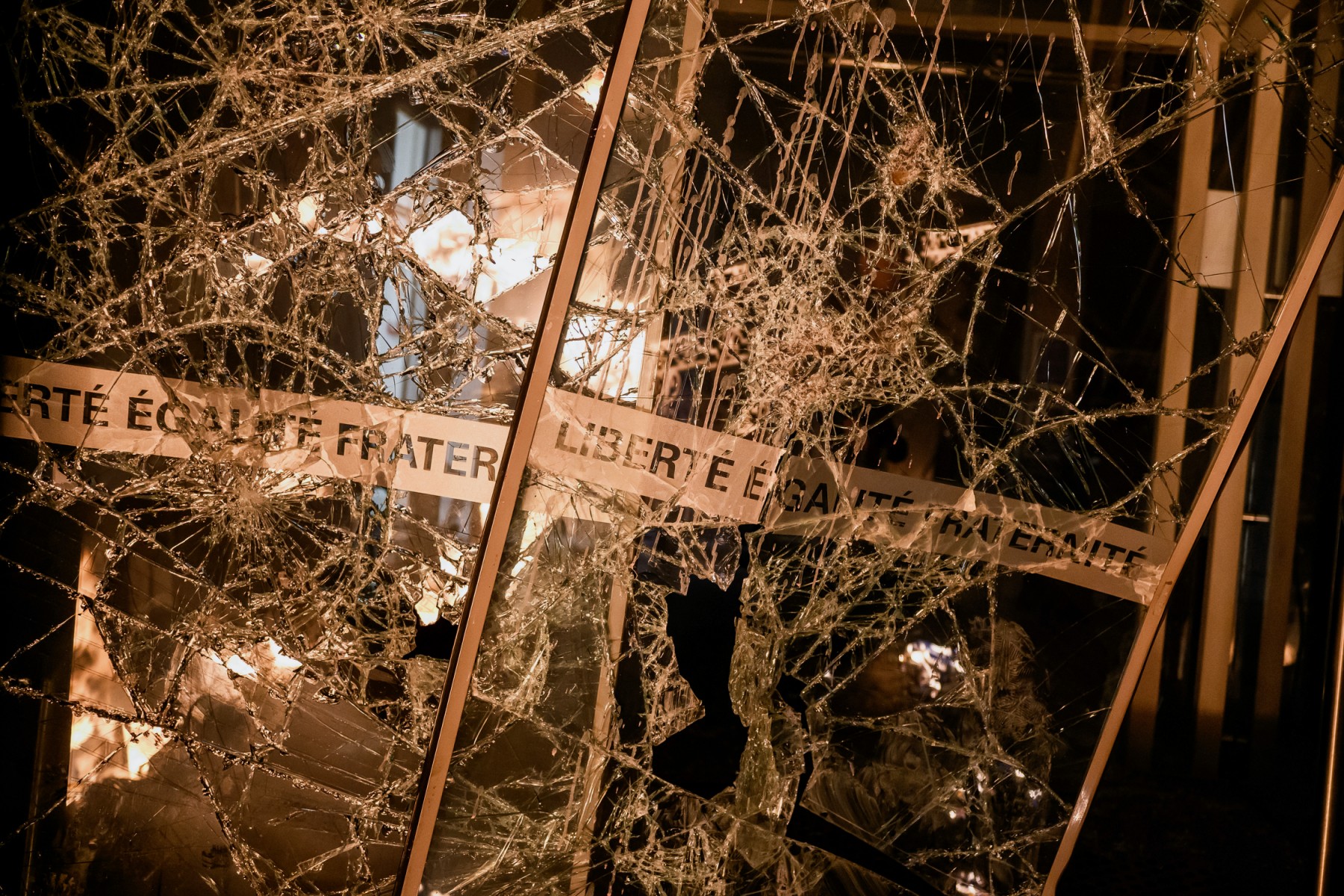 Des marques d'impact et des éclats de verre sont visibles sur les portes vandalisées à l'entrée de la mairie du 4e arrondissement de Lyon suite à des émeutes dans le cadre d'une manifestation le 17 mars 2023 à Lyon, au lendemain de la réforme des retraites imposée par le gouvernement français en utilisant l'article 49.3 de la constitution. (Photo by Jeff Pachoud / AFP)