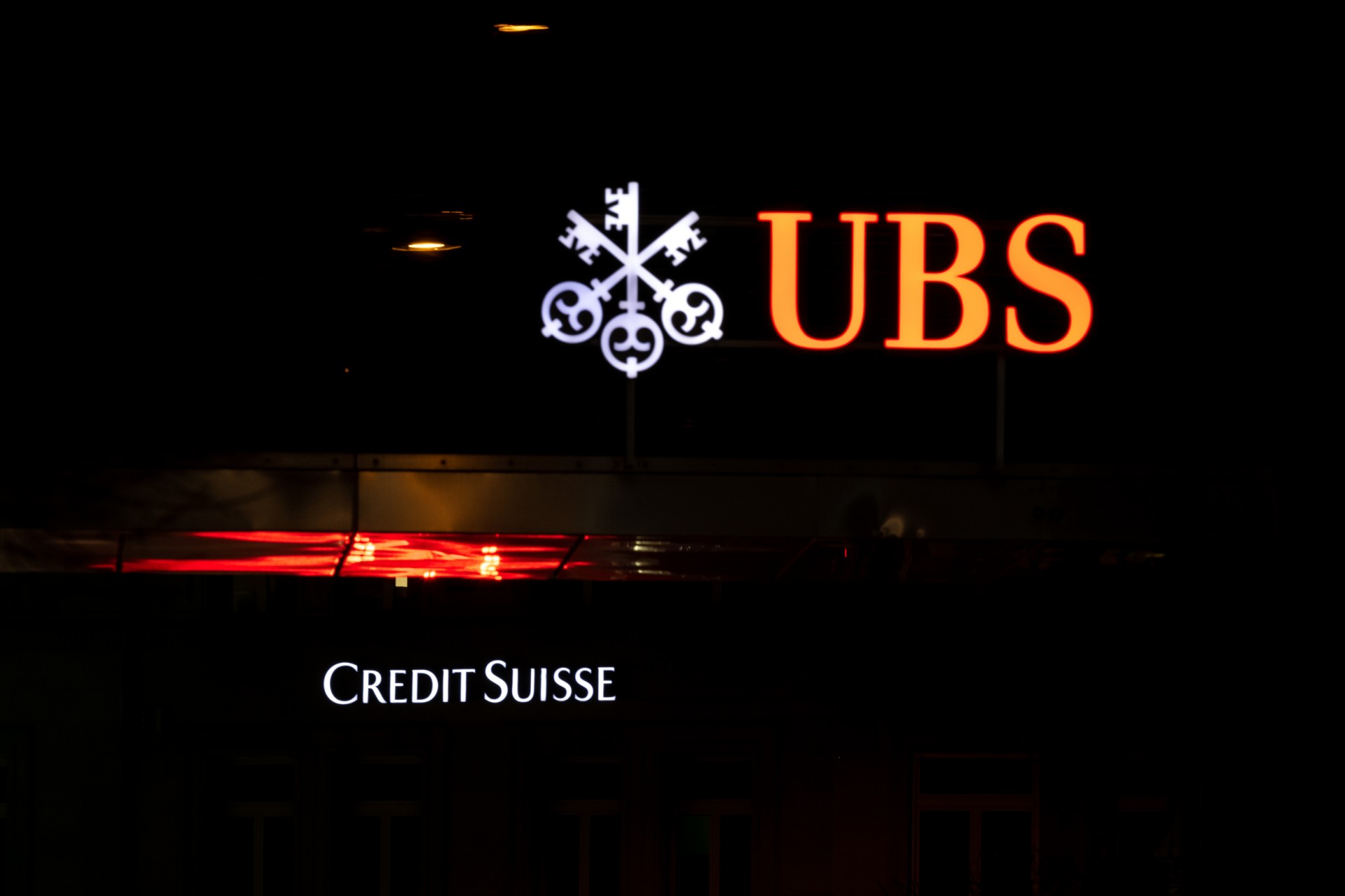 Un logo de la banque Credit Suisse est vu derrière un logo de la banque suisse UBS à Zurich le 18 mars 2023. (Photo par Fabrice Coffrini / AFP)