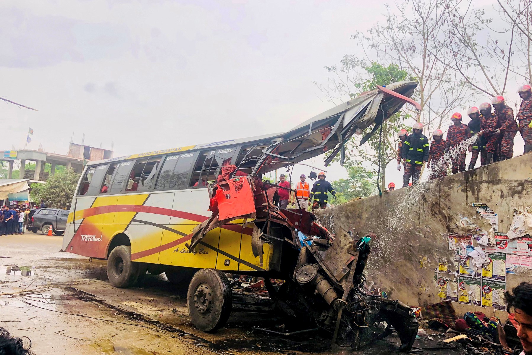Des pompiers éteignent un bus qui a eu un accident à Madaripur le 19 mars 2023. (Photo par AFP)
