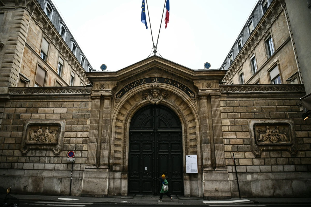 Cette photographie prise le 6 décembre 2022 montre un piéton passant devant l'entrée principale du bâtiment de la Banque de France à Paris. (Photo de Christophe Archambault / AFP)