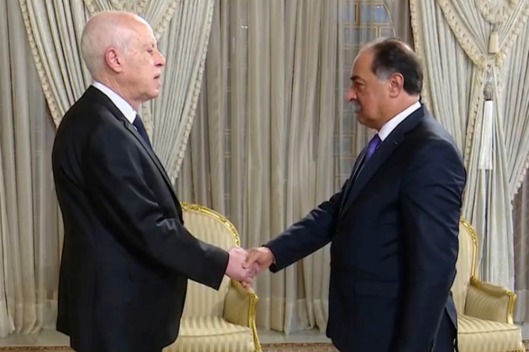 Un extrait d'une vidéo fournie par le service de presse de la présidence tunisienne montre le président Kais Saied (à gauche) serrant la main du nouveau ministre de l'Intérieur Kamal Feki lors de sa cérémonie de prestation de serment au palais présidentiel de Carthage, le 18 mars 2023. (Photo de la présidence tunisienne / AFP)