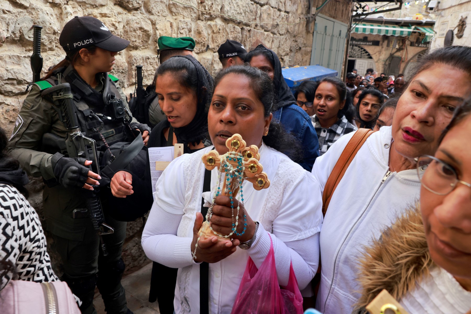 Les gardes-frontières israéliens regardent les pèlerins porter des croix de bois le long de la Via Dolorosa (chemin de la souffrance) dans la vieille ville de Jérusalem lors de la procession catholique du Vendredi Saint le 7 avril 2023. (Photo par Menahem KAHANA / AFP)